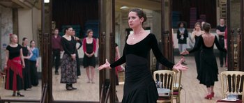 Movie still from “Happy-Go-Lucky” (2008), directed by Mike Leigh – A woman in a black dress standing in front of a group of people; Medium shot, Over the shoulder angle