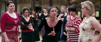 Movie still from “Happy-Go-Lucky” (2008), directed by Mike Leigh – A group of women standing in a room; Medium shot, Over the shoulder angle