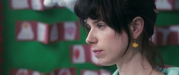 Movie still from “Happy-Go-Lucky” (2008), directed by Mike Leigh – A person with short black hair; Close Up shot, Over the shoulder angle