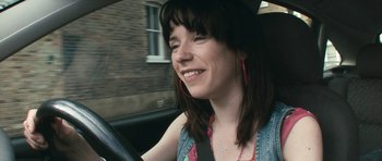 Movie still from “Happy-Go-Lucky” (2008), directed by Mike Leigh – A woman driving in a car with a smile on her face; Close Up shot, High angle