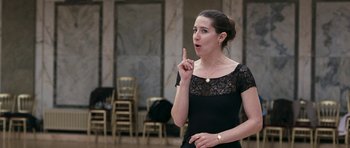 Movie still from “Happy-Go-Lucky” (2008), directed by Mike Leigh – A woman in a black dress is pointing to her face; Close Up shot, Over the shoulder angle