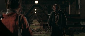 Movie still from “Happy-Go-Lucky” (2008), directed by Mike Leigh – A man standing in the middle of an abandoned area; Medium shot, Over the shoulder angle