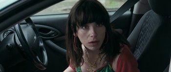 Movie still from “Happy-Go-Lucky” (2008), directed by Mike Leigh – A person in a car wearing a necklace; Close Up shot, Over the shoulder angle