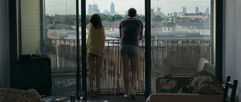 Movie still from “Happy-Go-Lucky” (2008), directed by Mike Leigh – A man and a woman looking out of a window; Wide shot, Over the shoulder angle