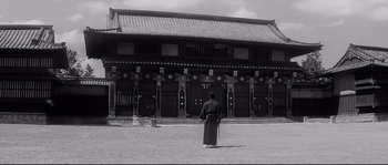 Movie still from “Harakiri” (1962), directed by Masaki Kobayashi – A man in a black robe standing in front of a building; Extreme Wide shot, Low angle