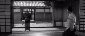 Movie still from “Harakiri” (1962), directed by Masaki Kobayashi – A man standing in front of a building holding a camera; Wide shot, Low angle