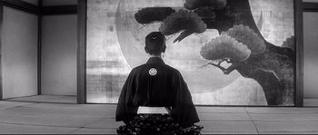 Movie still from “Harakiri” (1962), directed by Masaki Kobayashi – A woman sitting in front of a painting of flowers; Wide shot, Low angle