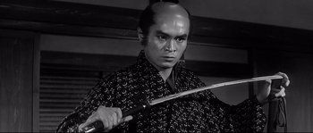 Movie still from “Harakiri” (1962), directed by Masaki Kobayashi – A man with a shaved head holding a sword; Close Up shot, Low angle