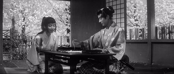 Movie still from “Harakiri” (1962), directed by Masaki Kobayashi – A man and a woman sitting at a wooden table; Medium shot, Over the shoulder angle