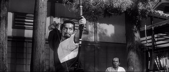 Movie still from “Harakiri” (1962), directed by Masaki Kobayashi – An old photo of a man holding a bow and arrow; Medium shot, Low angle