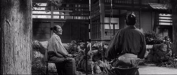 Movie still from “Harakiri” (1962), directed by Masaki Kobayashi – A black and white photo of a man sitting on a rock; Medium shot, Low angle