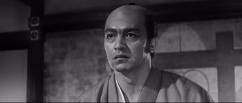 Movie still from “Harakiri” (1962), directed by Masaki Kobayashi – A black and white photo of a man with a shaved head; Close Up shot, Low angle