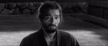 Movie still from “Harakiri” (1962), directed by Masaki Kobayashi – A black and white photo of a man with a beard; Close Up shot, Over the shoulder angle