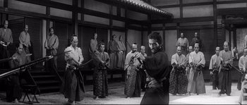 Movie still from “Harakiri” (1962), directed by Masaki Kobayashi – A group of men in traditional garb holding swords in a room; Wide shot, Over the shoulder angle