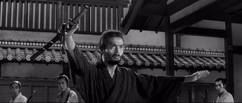 Movie still from “Harakiri” (1962), directed by Masaki Kobayashi – A black and white photo of a man holding a sword; Medium shot, Low angle