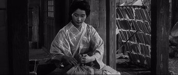 Movie still from “Harakiri” (1962), directed by Masaki Kobayashi – A woman in a kimono is sewing a bag; Medium shot, Low angle