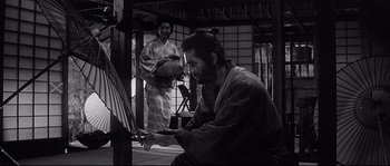 Movie still from “Harakiri” (1962), directed by Masaki Kobayashi – A man in a kimono painting with a brush; Medium shot, Over the shoulder angle