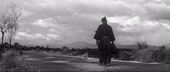 Movie still from “Harakiri” (1962), directed by Masaki Kobayashi – A man in a traditional japanese costume stands on the side of the road; Wide shot, Low angle