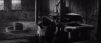 Movie still from “Harakiri” (1962), directed by Masaki Kobayashi – A man pouring liquid into a pot on top of a table; Wide shot, High angle