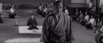 Movie still from “Harakiri” (1962), directed by Masaki Kobayashi – A black and white photo of a man with a camera; Wide shot, Over the shoulder angle