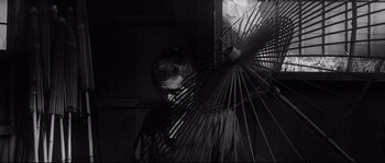 Movie still from “Harakiri” (1962), directed by Masaki Kobayashi – A man holding an open umbrella in a dark room; Medium shot, Low angle