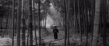 Movie still from “Harakiri” (1962), directed by Masaki Kobayashi – A man riding a motorcycle down a dirt path through the woods; Wide shot, Low angle