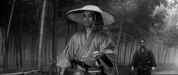 Movie still from “Harakiri” (1962), directed by Masaki Kobayashi – A man wearing a hat and holding two swords; Medium shot, Low angle