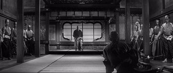 Movie still from “Harakiri” (1962), directed by Masaki Kobayashi – A man sitting on the ground in front of an audience; Wide shot, Low angle