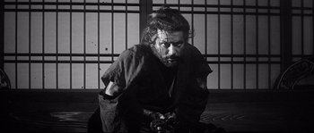 Movie still from “Harakiri” (1962), directed by Masaki Kobayashi – A man with a beard is holding a camera in his hands; Medium shot, Low angle