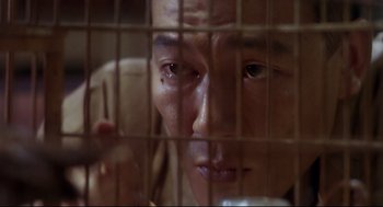 Movie still from “Hard Boiled” (1992), directed by John Woo – A man looking through the bars of a cell phone cage; Extreme Close Up shot, Low angle