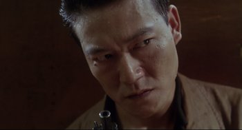 Movie still from “Hard Boiled” (1992), directed by John Woo – A person with a gun in his hand; Close Up shot, Low angle