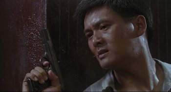 Movie still from “Hard Boiled” (1992), directed by John Woo – A person holding a gun; Close Up shot, Low angle