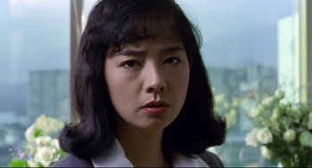 Movie still from “Hard Boiled” (1992), directed by John Woo – A young woman with long black hair looking at the camera; Close Up shot, Low angle