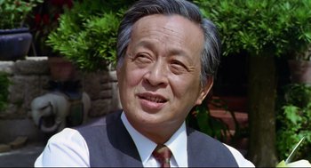 Movie still from “Hard Boiled” (1992), directed by John Woo – An older man wearing a vest and a tie; Close Up shot, Low angle