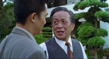 Movie still from “Hard Boiled” (1992), directed by John Woo – A man in a suit and tie talking to another man in a suit and tie; Close Up shot, Over the shoulder angle