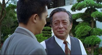 Movie still from “Hard Boiled” (1992), directed by John Woo – A man in a suit talking to another man in a suit; Close Up shot, Over the shoulder angle