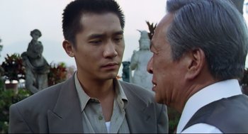 Movie still from “Hard Boiled” (1992), directed by John Woo – A man in a suit talking to another man in a suit; Close Up shot, Over the shoulder angle