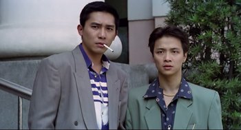 Movie still from “Hard Boiled” (1992), directed by John Woo – Two young men standing next to each other with a cigarette in their mouth; Medium shot, Low angle