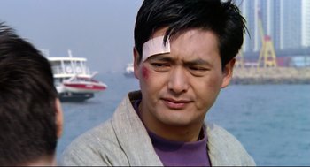 Movie still from “Hard Boiled” (1992), directed by John Woo – A man with bandage on his head and a boat in the background; Close Up shot, Low angle