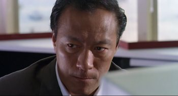 Movie still from “Hard Boiled” (1992), directed by John Woo – A person wearing a suit and tie; Close Up shot, Low angle