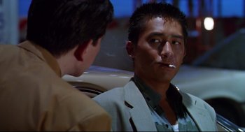 Movie still from “Hard Boiled” (1992), directed by John Woo – A man sitting next to another man smoking a cigarette; Close Up shot, Low angle