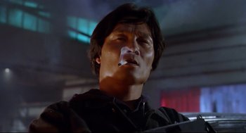 Movie still from “Hard Boiled” (1992), directed by John Woo – A man smoking a cigarette while sitting in a chair; Close Up shot, Low angle