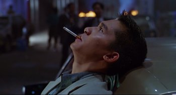 Movie still from “Hard Boiled” (1992), directed by John Woo – A man with a cigarette in his mouth looking up; Close Up shot, Low angle