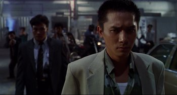 Movie still from “Hard Boiled” (1992), directed by John Woo – A person wearing a suit and tie; Close Up shot, Low angle