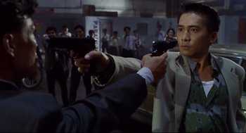 Movie still from “Hard Boiled” (1992), directed by John Woo – A group of people holding guns in a room; Medium shot, Over the shoulder angle