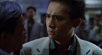 Movie still from “Hard Boiled” (1992), directed by John Woo – A person wearing a suit and tie; Close Up shot, Over the shoulder angle