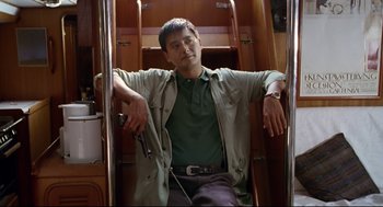Movie still from “Hard Boiled” (1992), directed by John Woo – A man holding a gun while standing on a staircase; Medium shot, Low angle