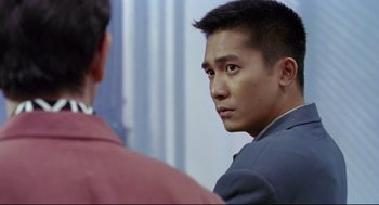 Movie still from “Hard Boiled” (1992), directed by John Woo – A man in a suit looking at another man in a red shirt; Close Up shot, Over the shoulder angle