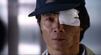 Movie still from “Hard Boiled” (1992), directed by John Woo – A person wearing a hat and eye patch; Close Up shot, Low angle