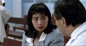 Movie still from “Hard Boiled” (1992), directed by John Woo – An asian woman sitting next to an older man; Close Up shot, Over the shoulder angle